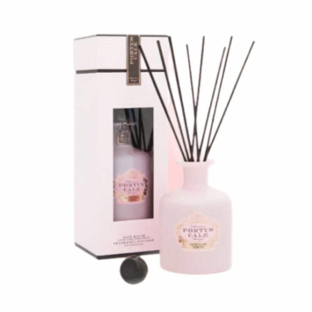 מפיץ ריח 250 מ"ל Rose Blush Portus Cale עם מקלות שחורים מוצג לצד האריזה התואמת בלבן וורוד. - vavaVoom.co.il
