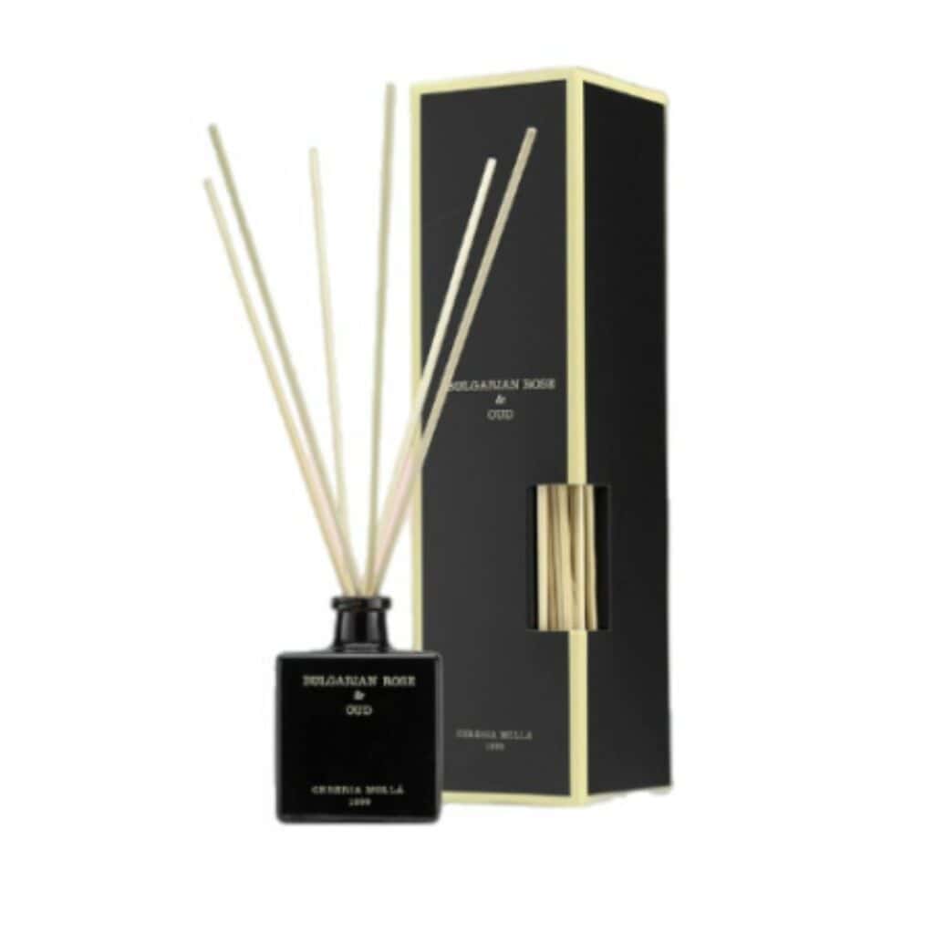 בקבוק מפיץ ריח שחור עם קנים דקים מעץ, לצד הקופסה התואמת בצבעי שחור וזהב. על התווית כתוב "מפיץ ריח BULGARIAN ROSE&OUT - מ״ל 100". - vavaVoom.co.il