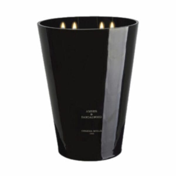 פמוט שחור גדול ומבריק עם ארבע להבות נושא את התווית "נר ענק AMBER&SANDALWOOD - ק״ג 3.5" מבית Cereria Molla 1899. המוצר מוצג על רקע לבן חלק. - vavaVoom.co.il