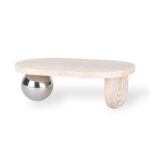 המגש טרוונטין אובלי רגל כדור ניקל הוא שולחן קפה מודרני עם משטח עליון סגלגל בצבע שמנת, דמוי אבן, רגל עץ מעוגלת אחת ורגל אחת בצורת כדור ניקל מבריק, מוצג על רקע לבן. - vavaVoom.co.il